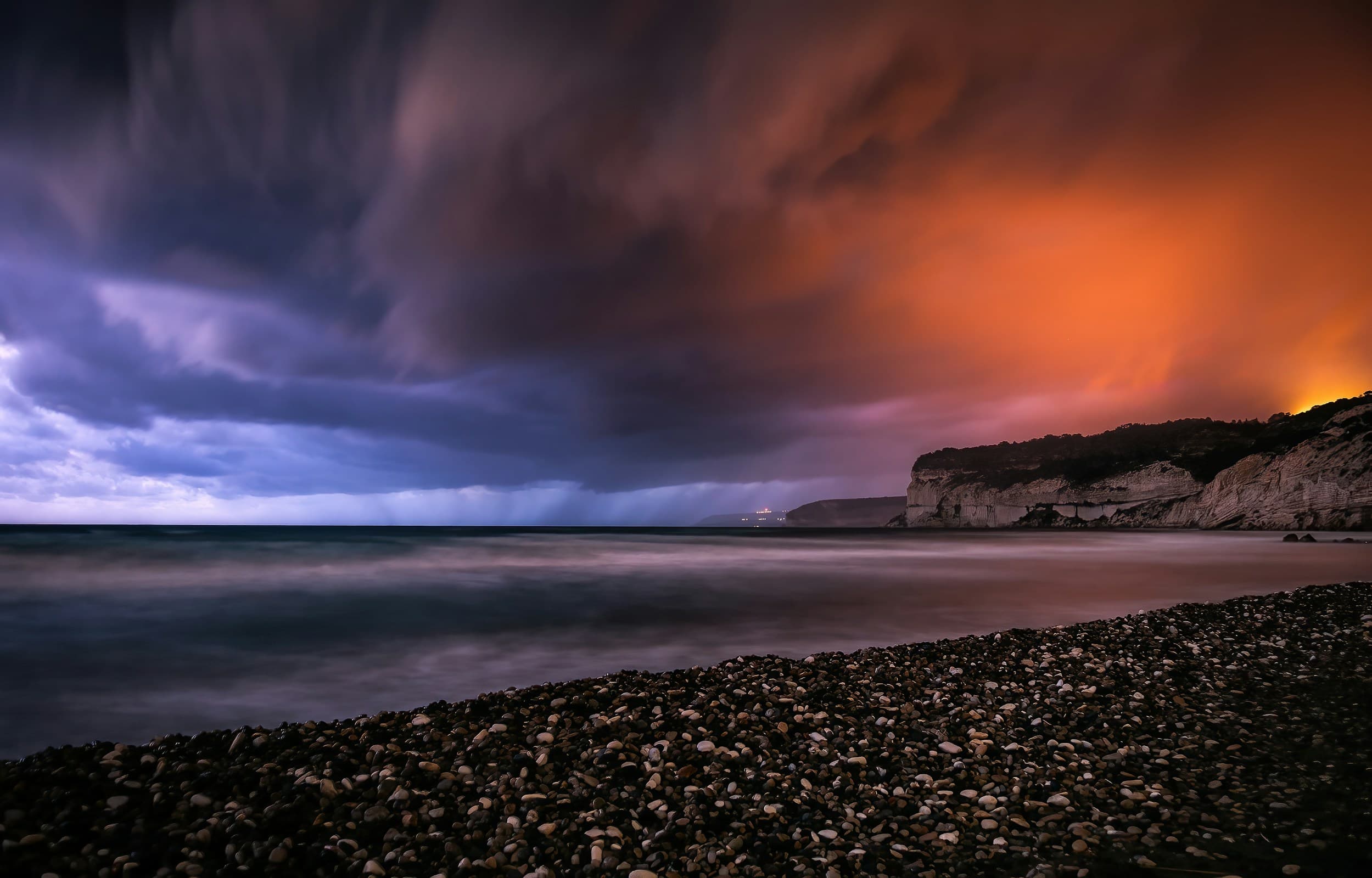 Dramatic storm clouds over coastal cliffs at dusk